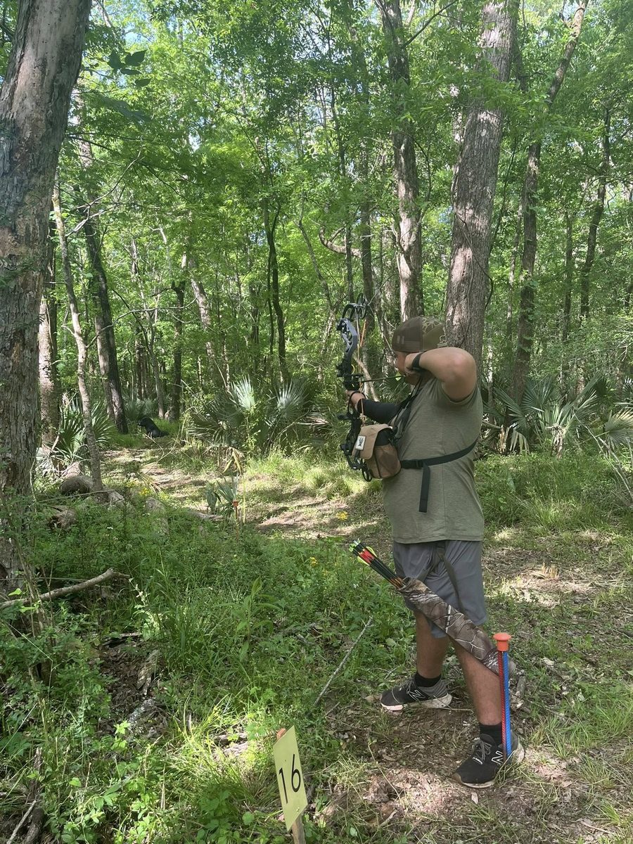 An Assumption 4-H archer taking aim on a 3D archery course
